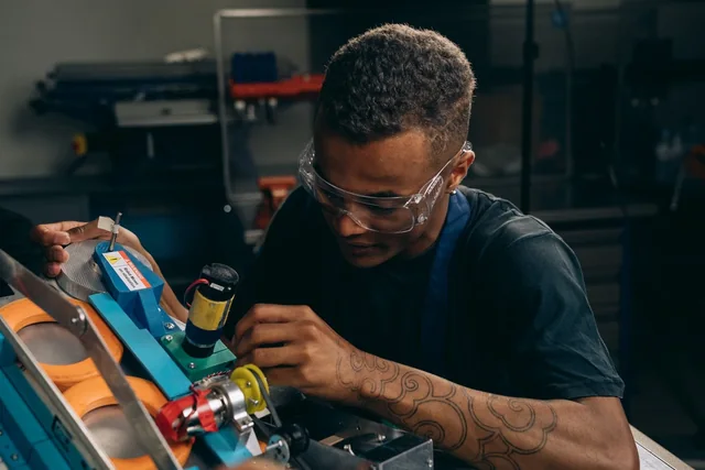 Engineer in safety glasses assembling equipment at a bench